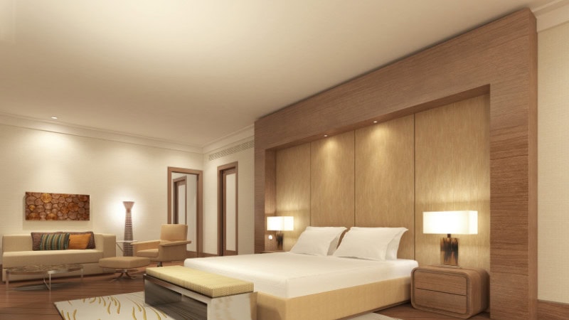 Stylish hotel bedroom with warm wall lighting, a wooden feature wall, and comfortable seating.