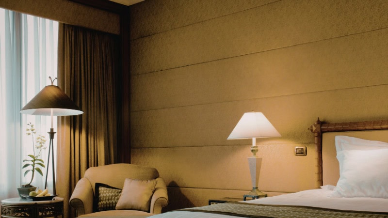 Inviting hotel room with soft ambient lighting, a comfortable armchair, and elegant lamps.