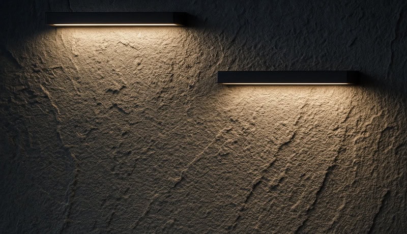Black linear wall light performing wall grazing on rough texture wall