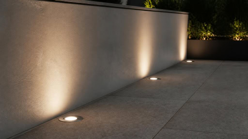 Recessed in‑ground light casts warm glow on exterior building wall