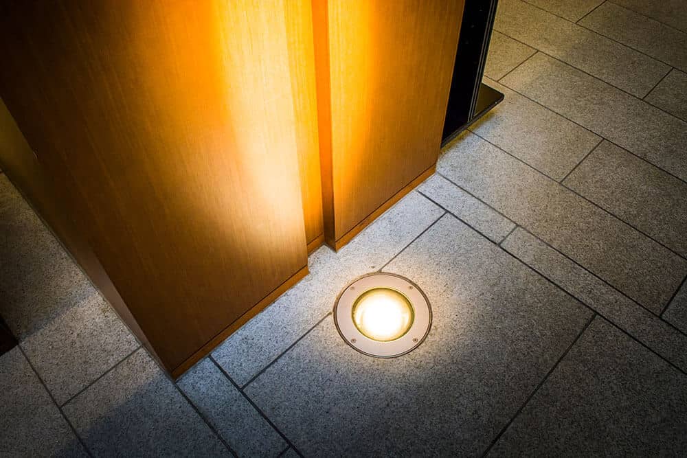 In‑ground light illuminates outdoor stone pavement