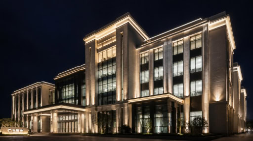 Modern classical office building with elegant warm facade lighting at night